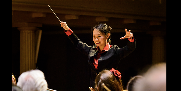 Young woman conducting an orchestra and smiling