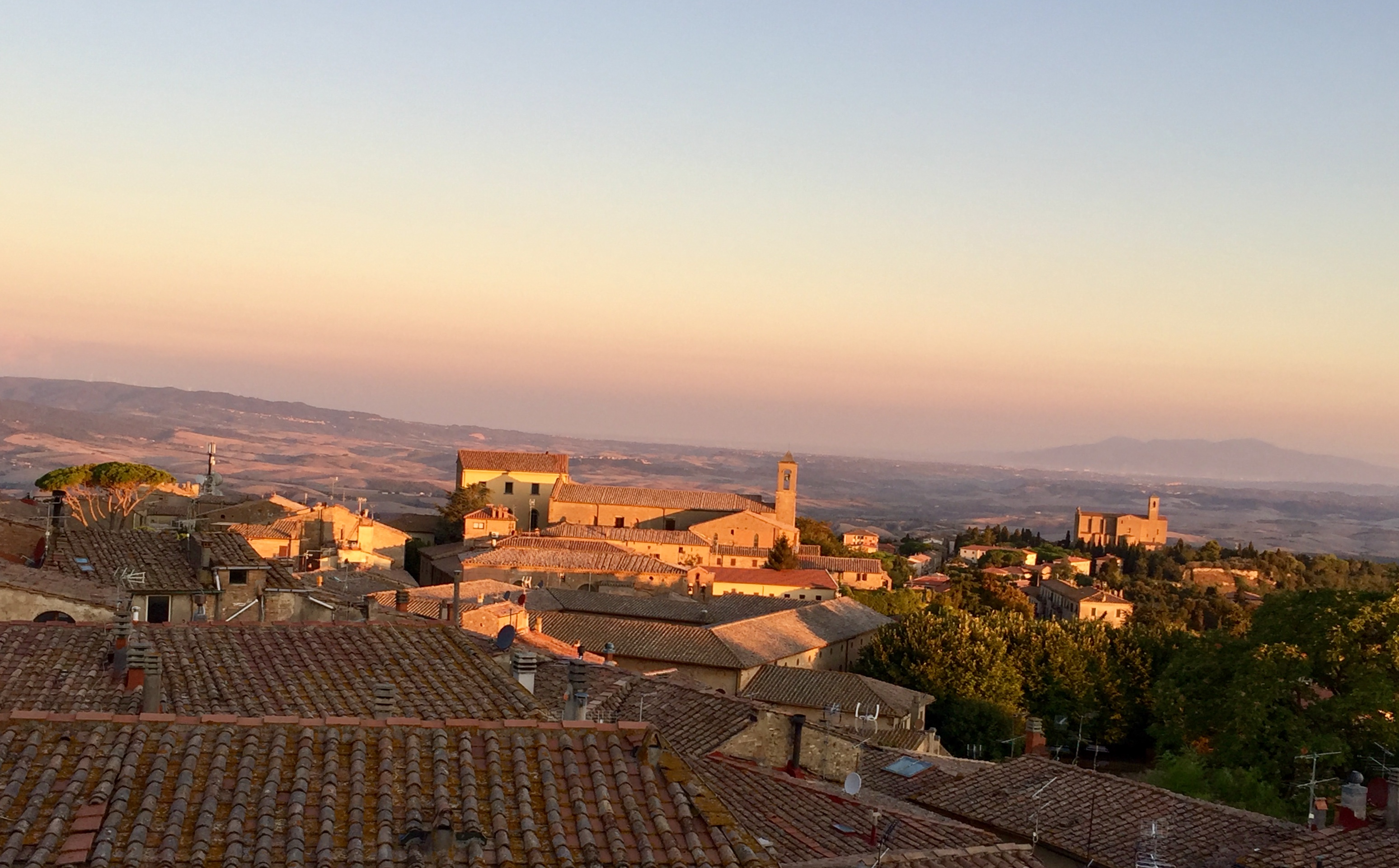 Travel snap of early morning view of the Tuscan countryside over rooftops and church spires.