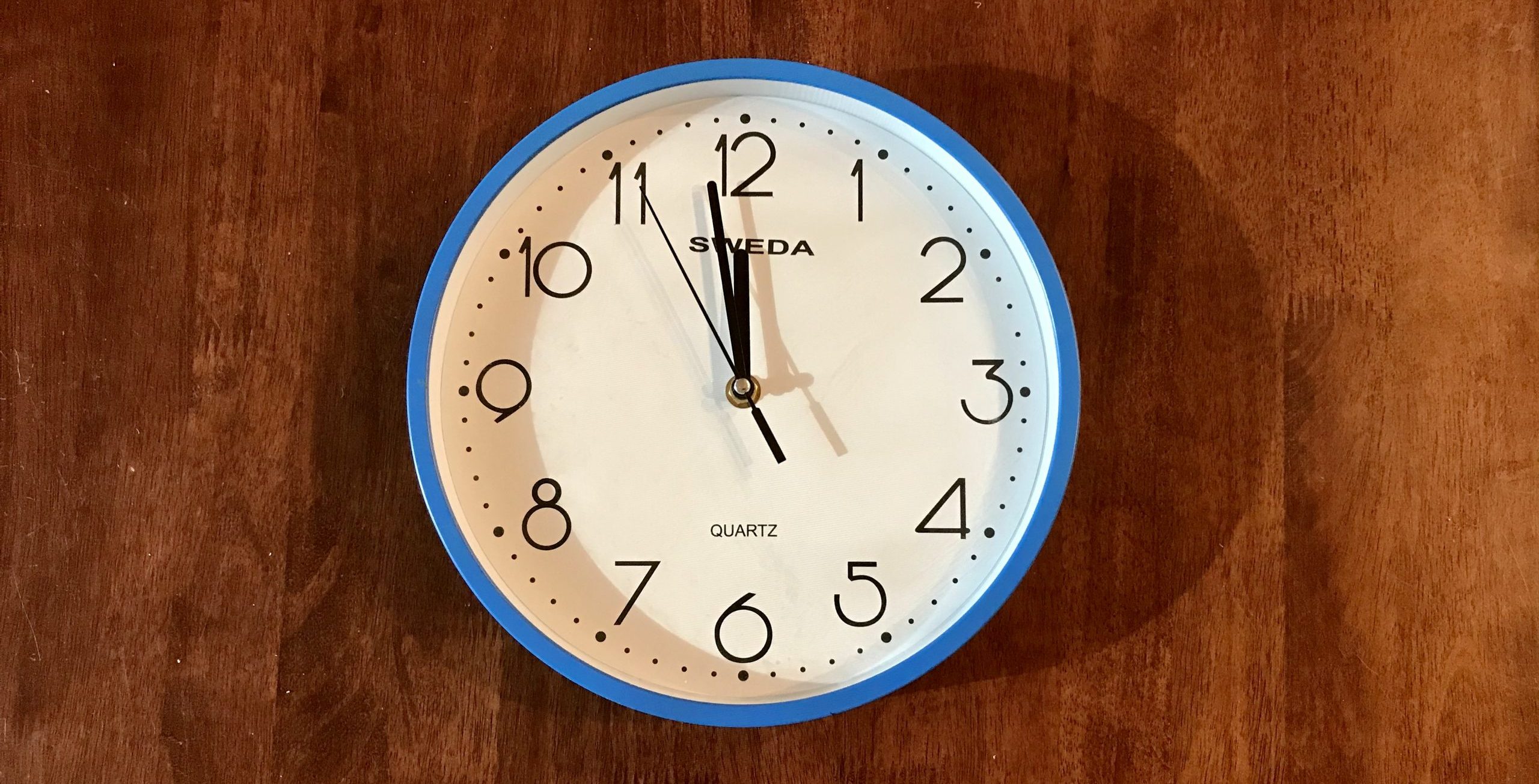 Analogue clock showing one minute to midnight