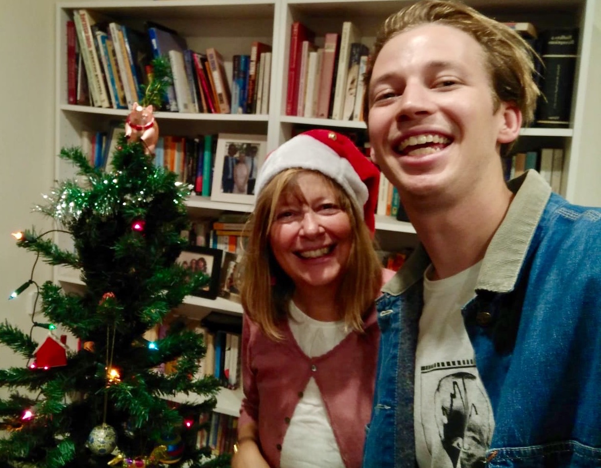 A mother and son smiling in front of a Christmas tree